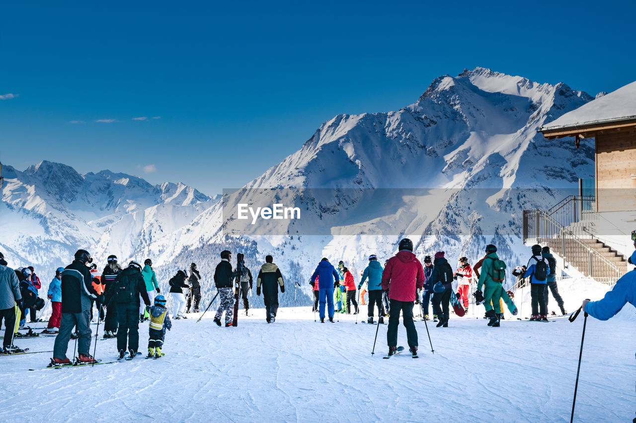 People on snow covered field against sky