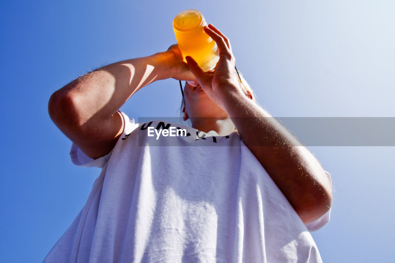 Low angle view of woman drinking against sky