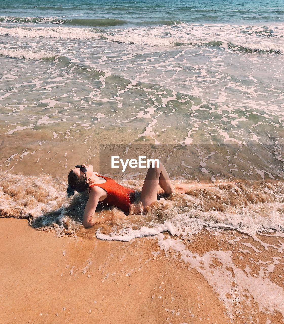 Side view of woman lying on shore at beach