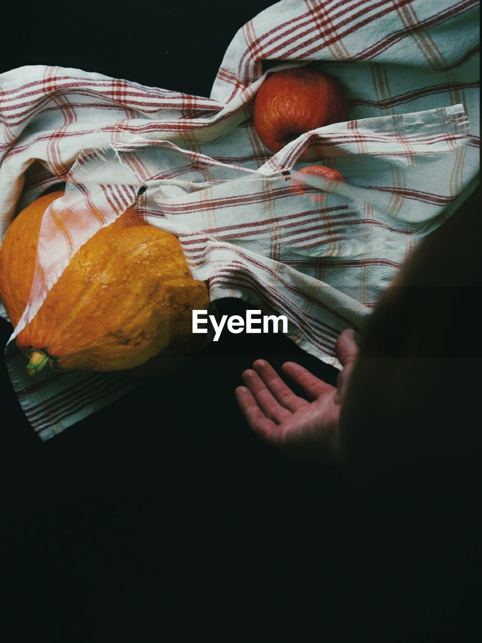 Close-up of hand, kitchen towel and pumpkin