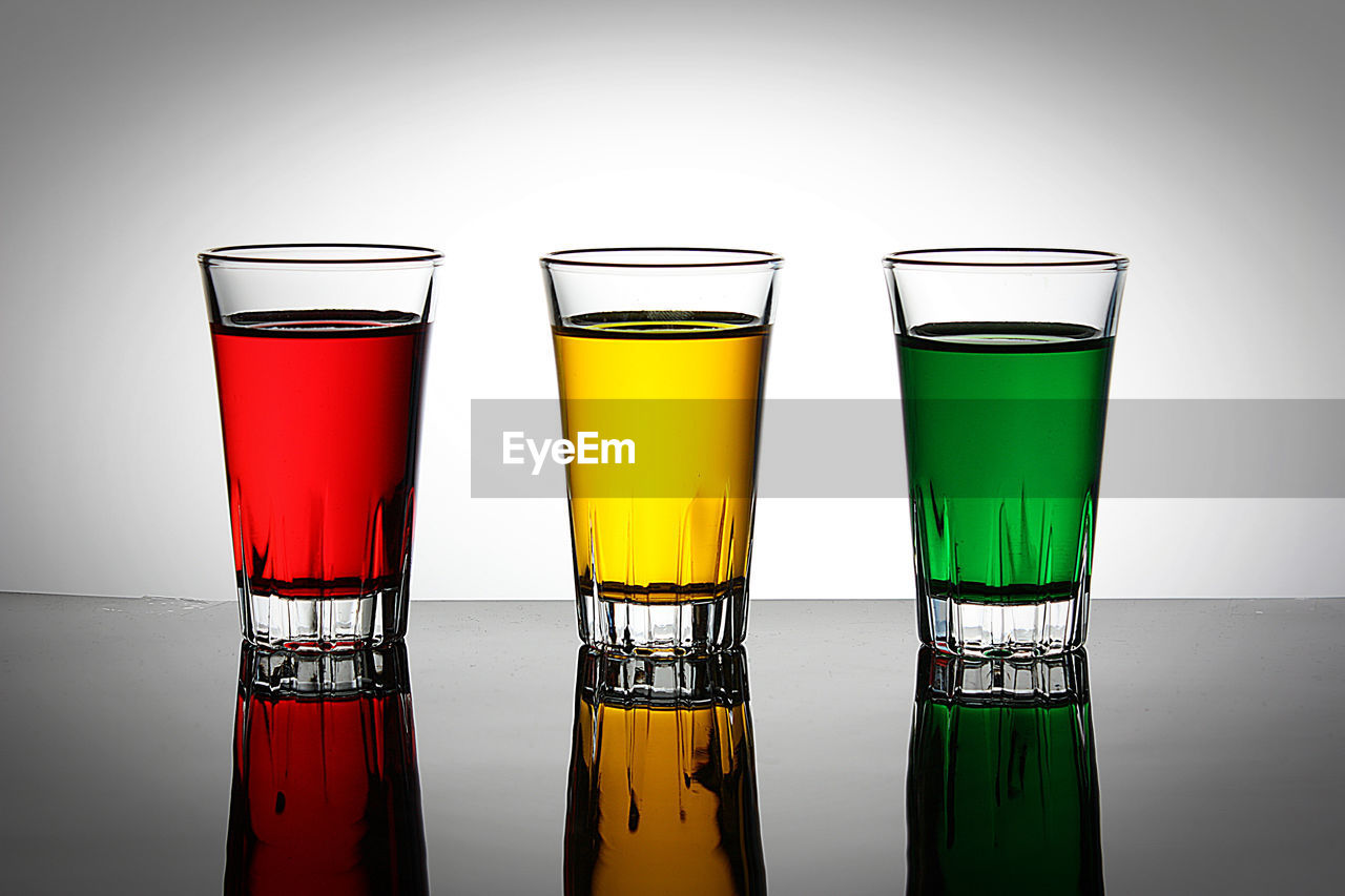 Close-up of drinking glasses on table against white background