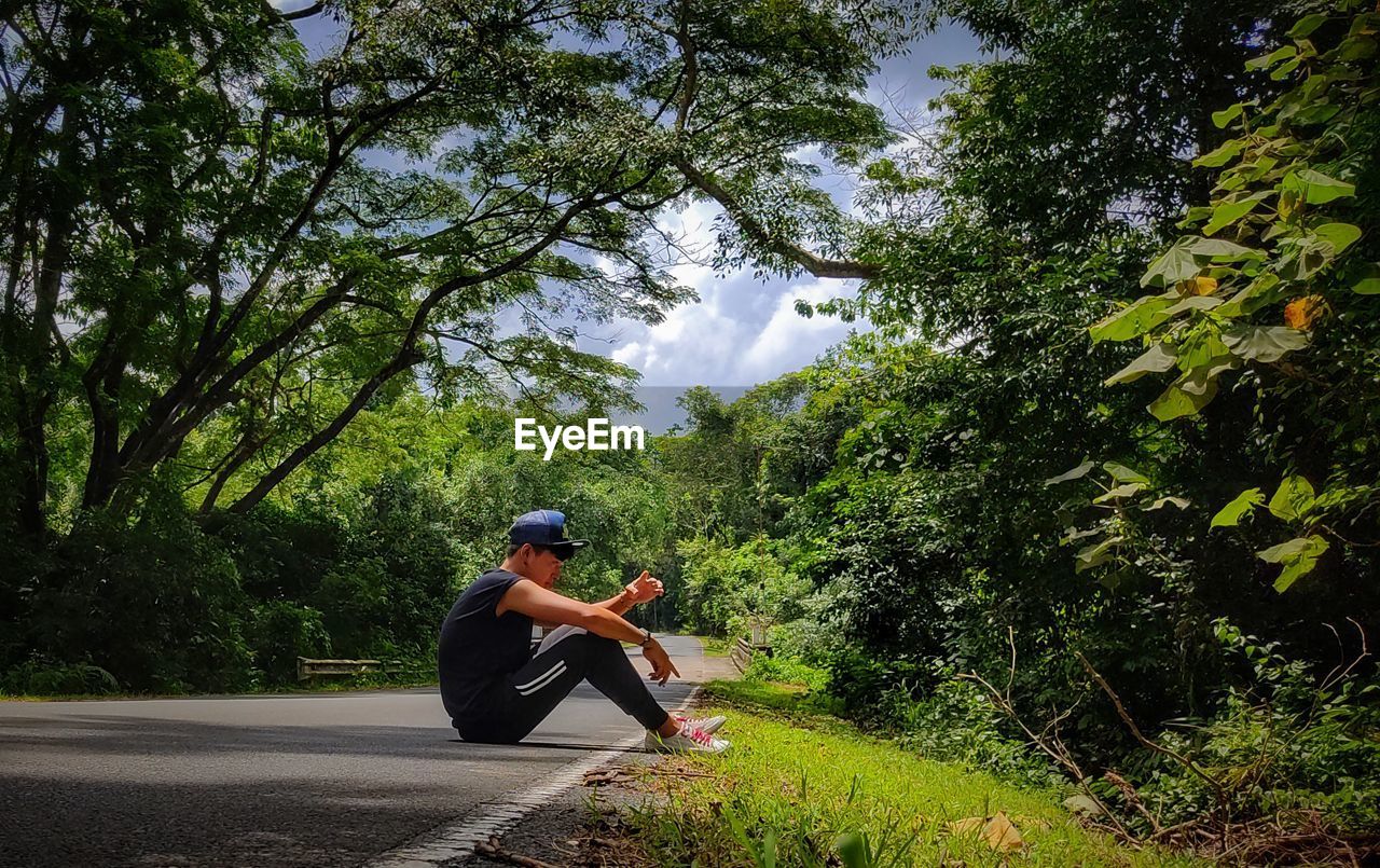 Side view of man sitting in forest