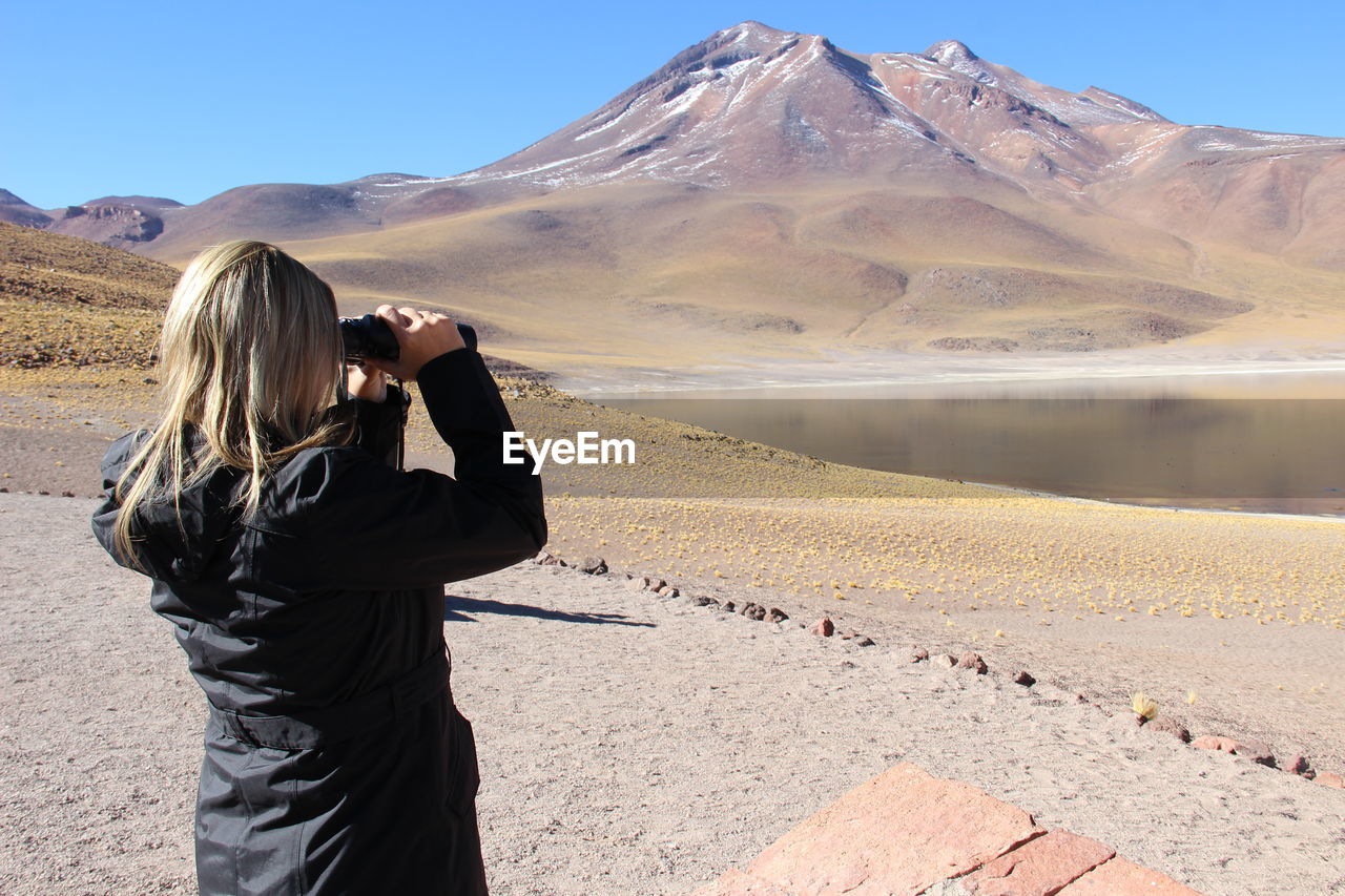 Woman looking through binoculars at desert