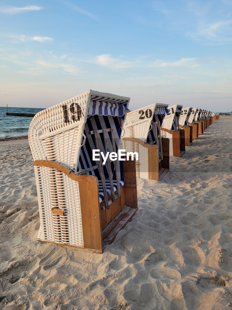 HOODED BEACH CHAIRS ON SAND AGAINST SEA