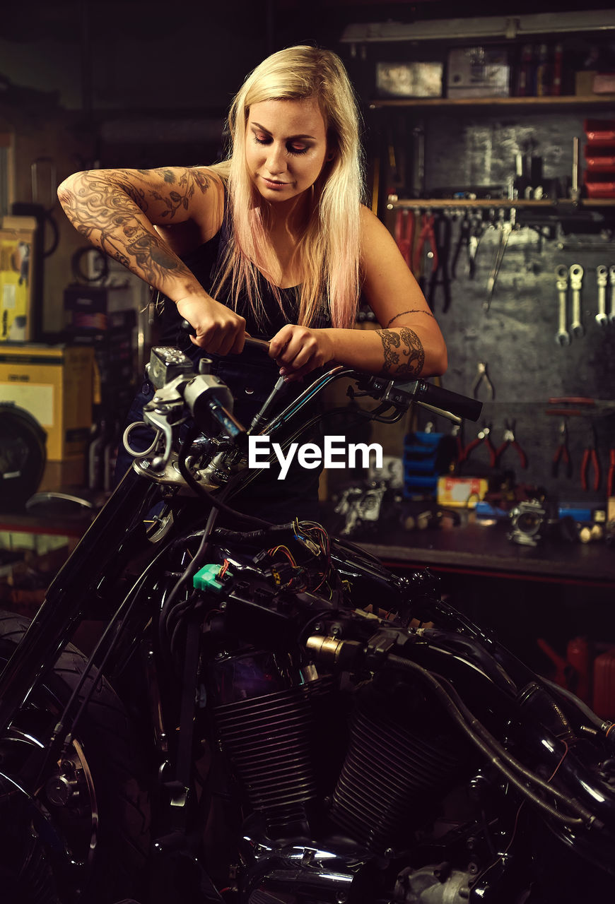 Woman repairing motorcycle at workshop