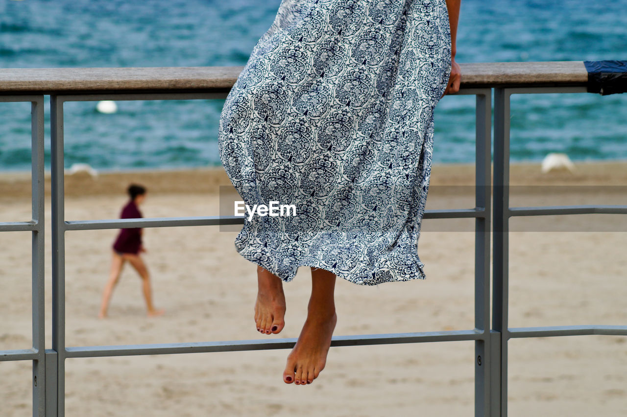 Low section of woman sitting on railing