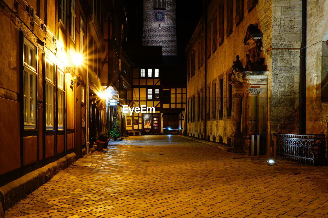 Empty alley amidst buildings in city at night