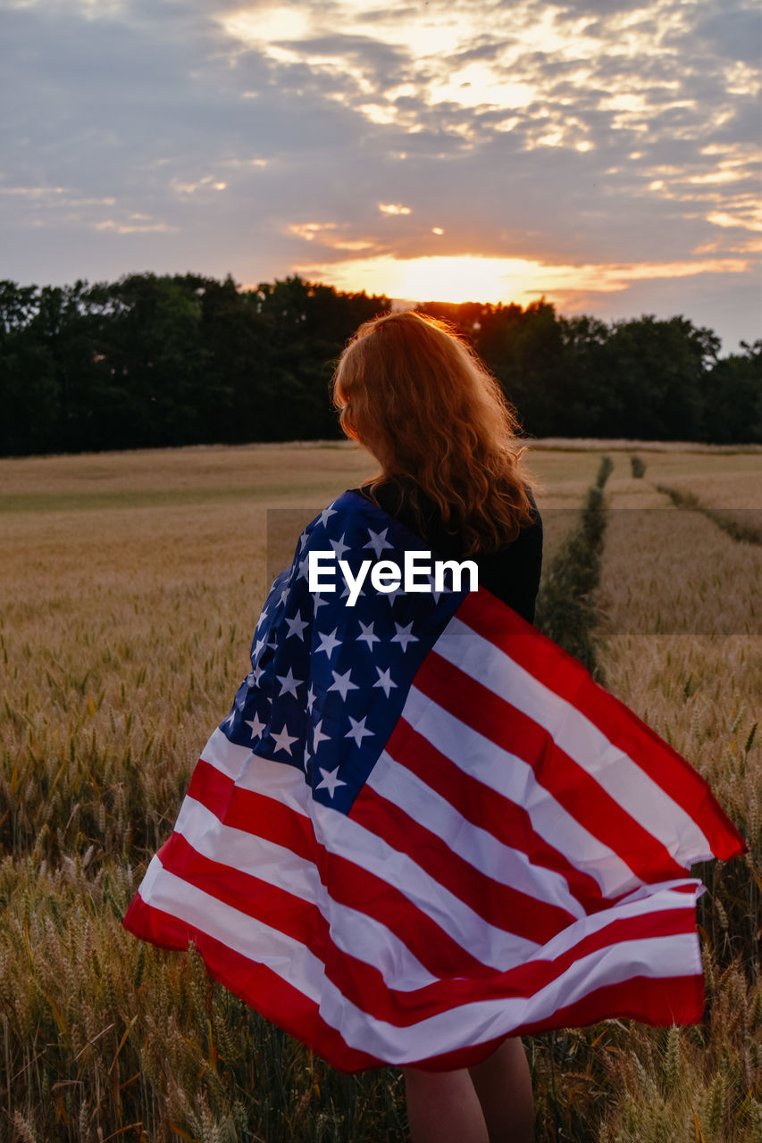 Rear view of woman with american flag on field