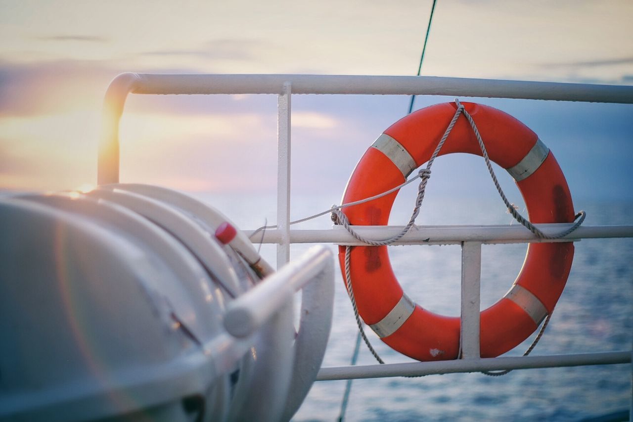 Life belt hanging on boat in sea during sunrise