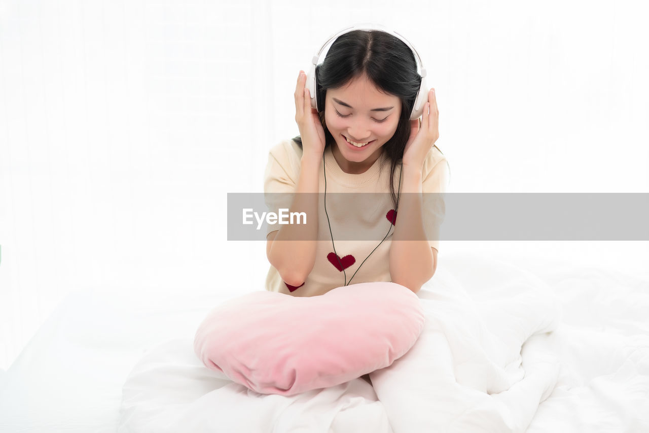 Young woman sitting on bed