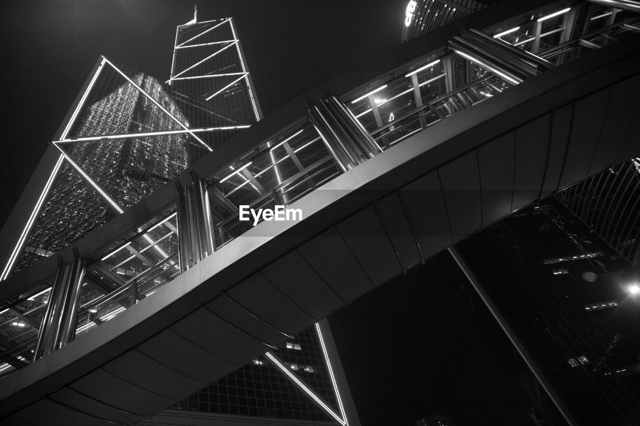 Low angle view of footbridge by illuminated bank of china tower against sky