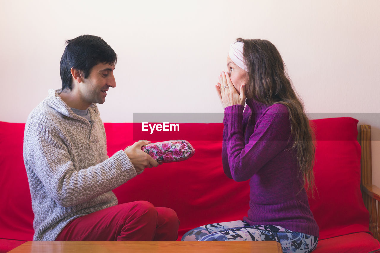 SIDE VIEW OF YOUNG COUPLE SITTING