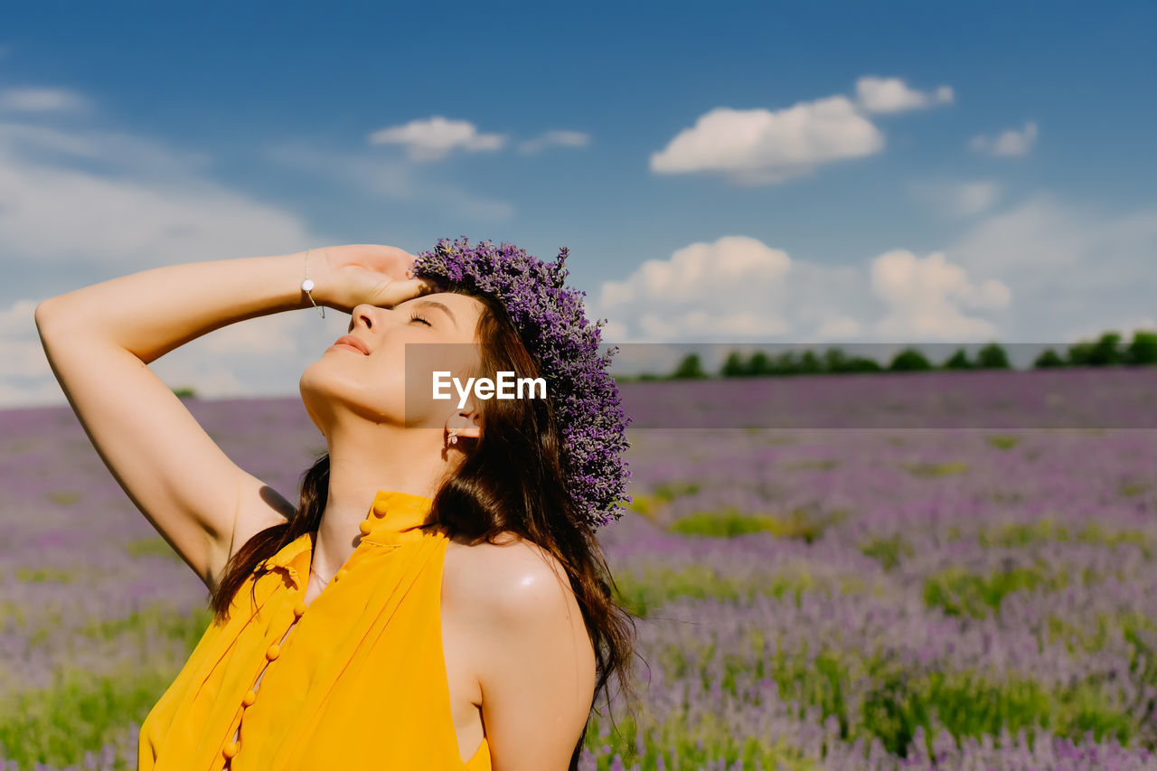 Young woman standing against sky