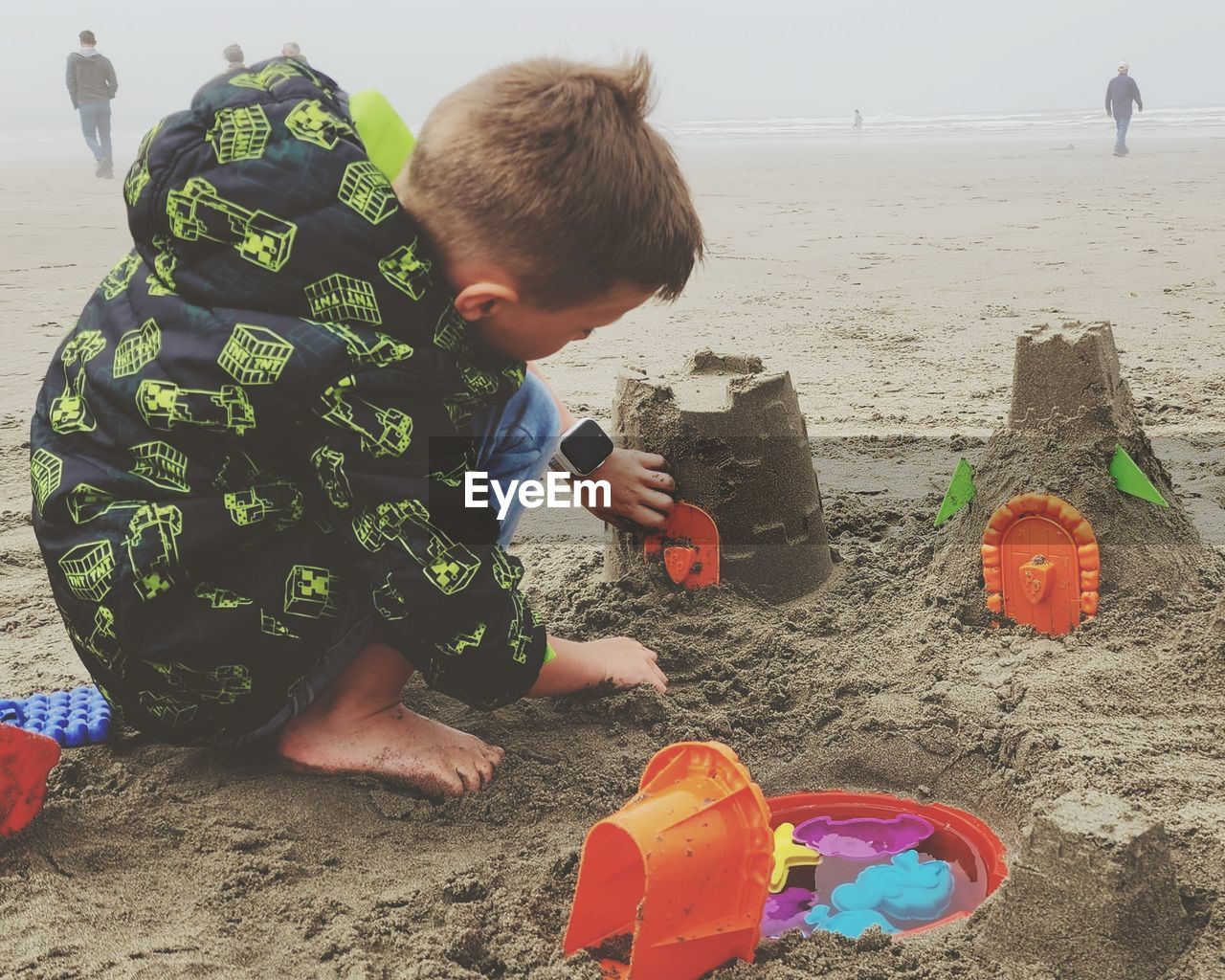 beach, sand, land, childhood, child, men, sand pail and shovel, sea, nature, water, leisure activity, toy, holiday, full length, trip, vacation, lifestyles, day, person, bucket, one person, sky, toddler, crouching, outdoors, sandcastle, fun, summer, clothing, preschool, container