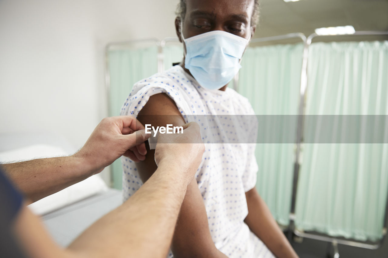 Nurse with adhesive bandage on patient's arm in medical room