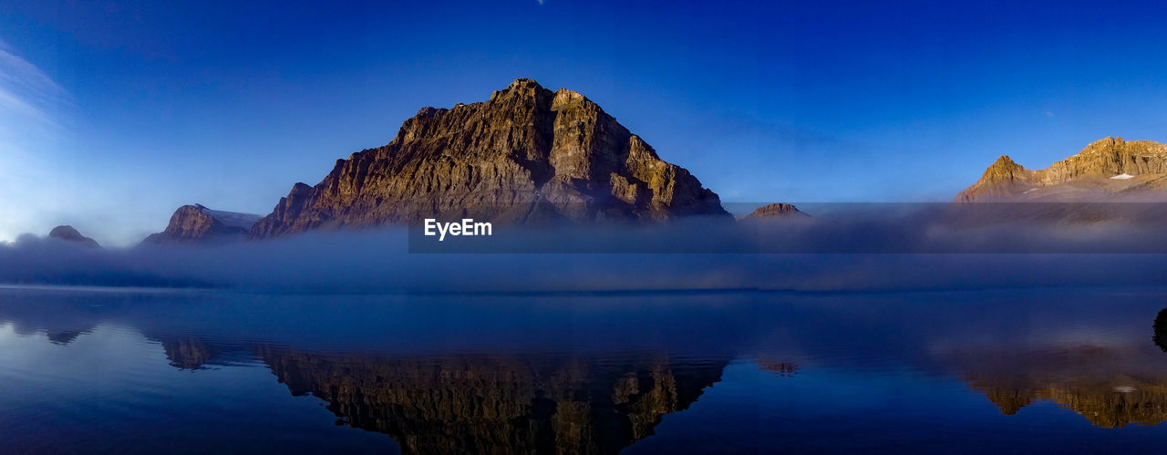 Panoramic view of lake and rocks against blue sky