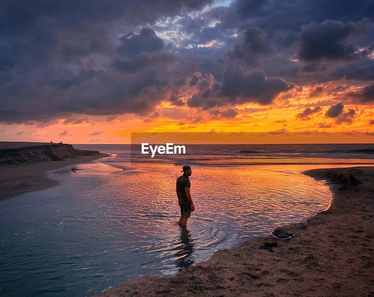 Man standing on beach against sky during sunset