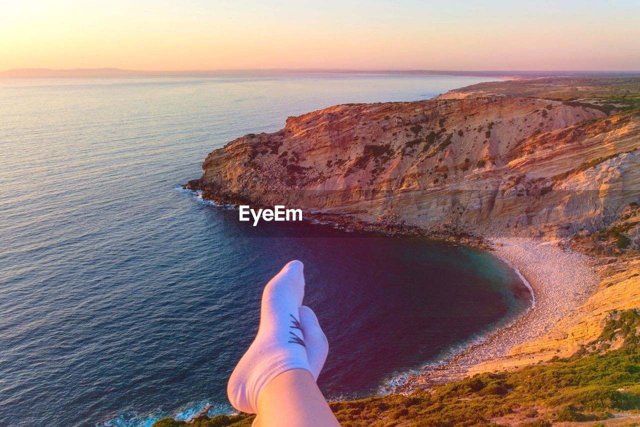 Low section of person on mountain during sunset