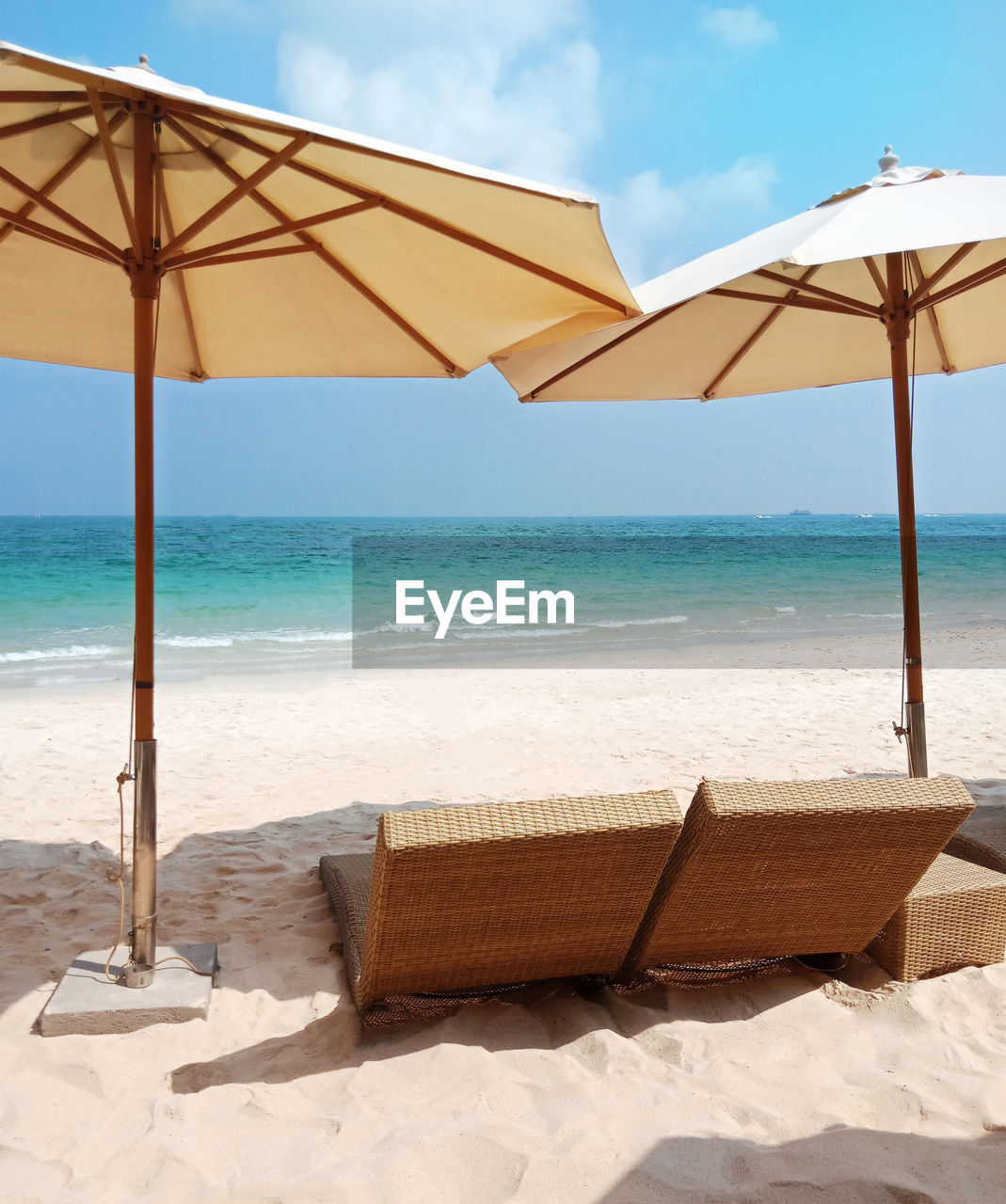 LOUNGE CHAIRS ON BEACH AGAINST SEA