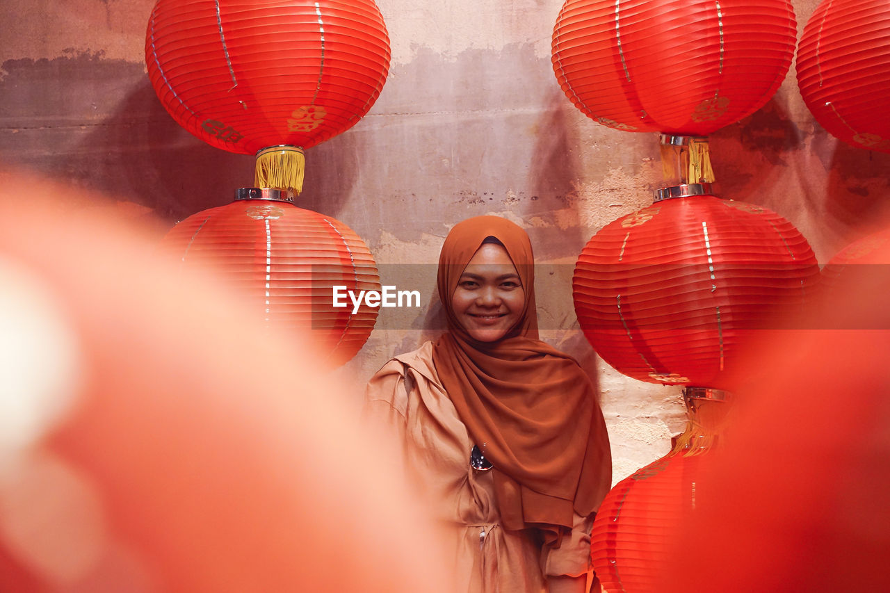 Smiling woman standing against lanterns