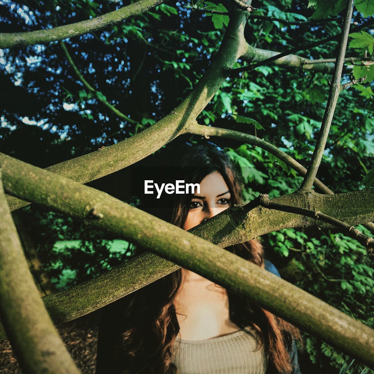 Woman looking away while standing by tree