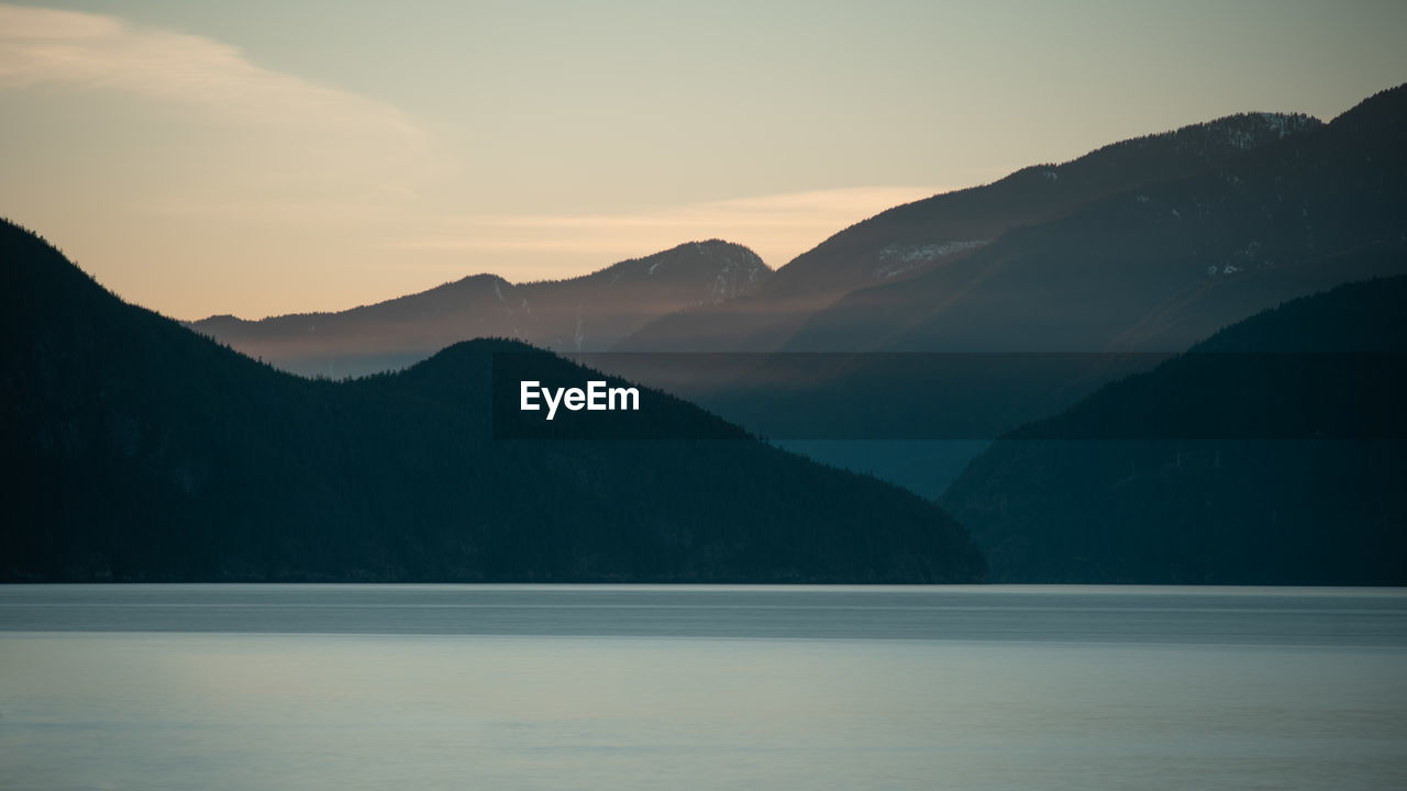 Scenic view of lake and mountains against sky during sunset