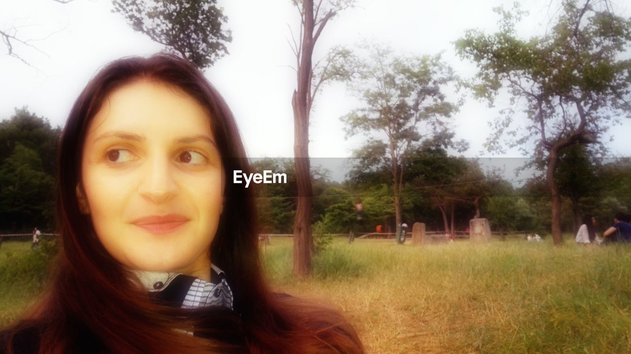 CLOSE-UP PORTRAIT OF SMILING YOUNG WOMAN IN PARK