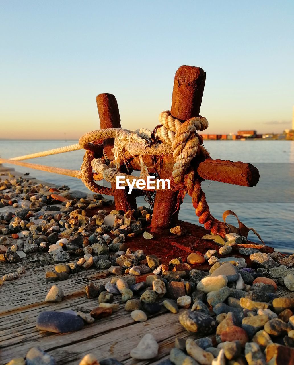 Close-up of mooring bolard on wooden pier against sunset sky