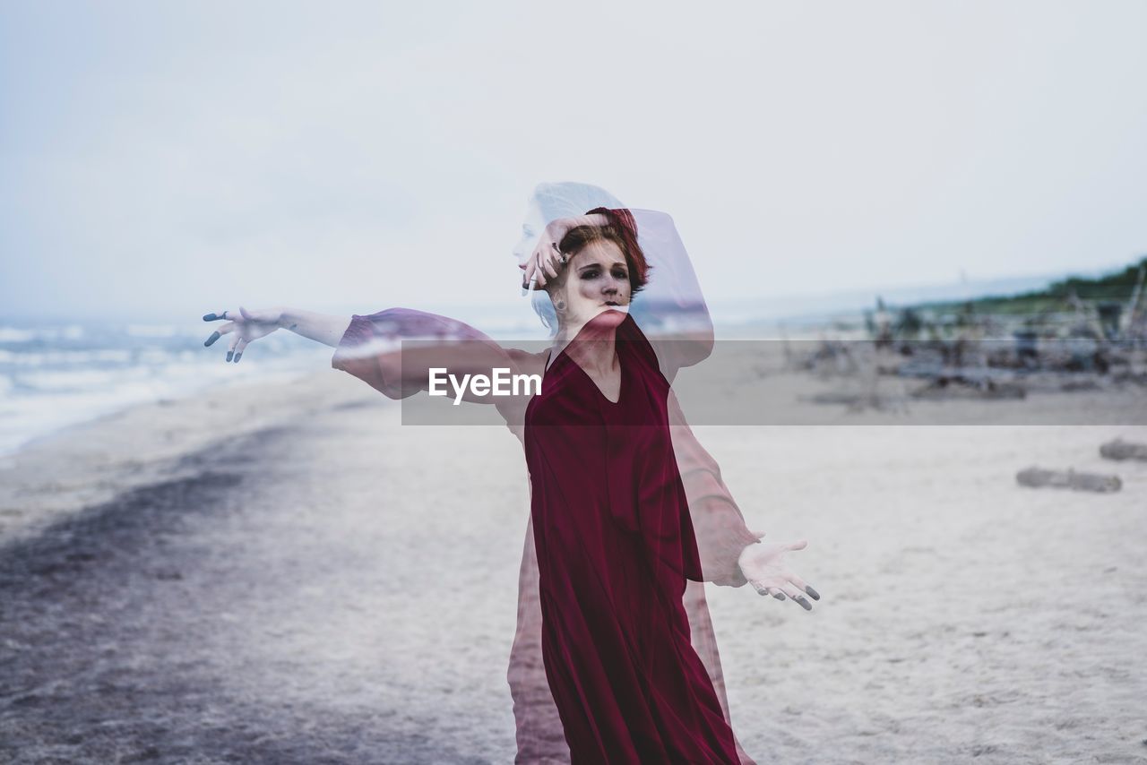 Blurred motion of woman standing at beach against clear sky