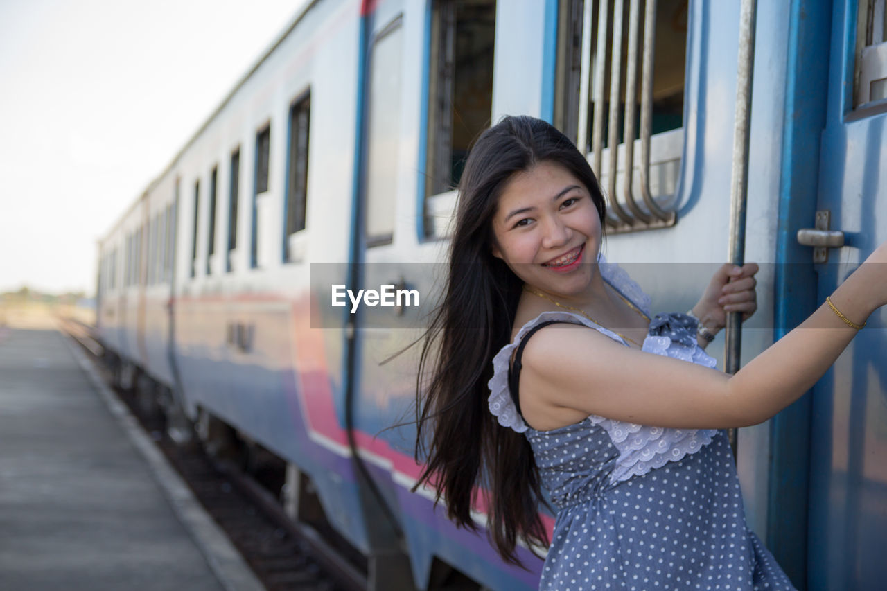Happy woman hanging at entrance of train