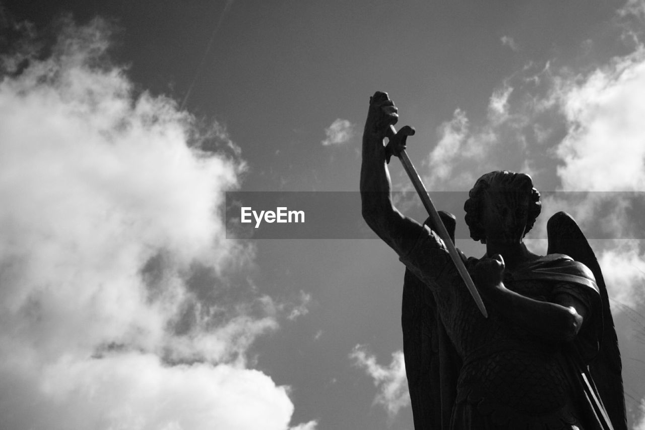 LOW ANGLE VIEW OF WOMAN HOLDING UMBRELLA AGAINST SKY