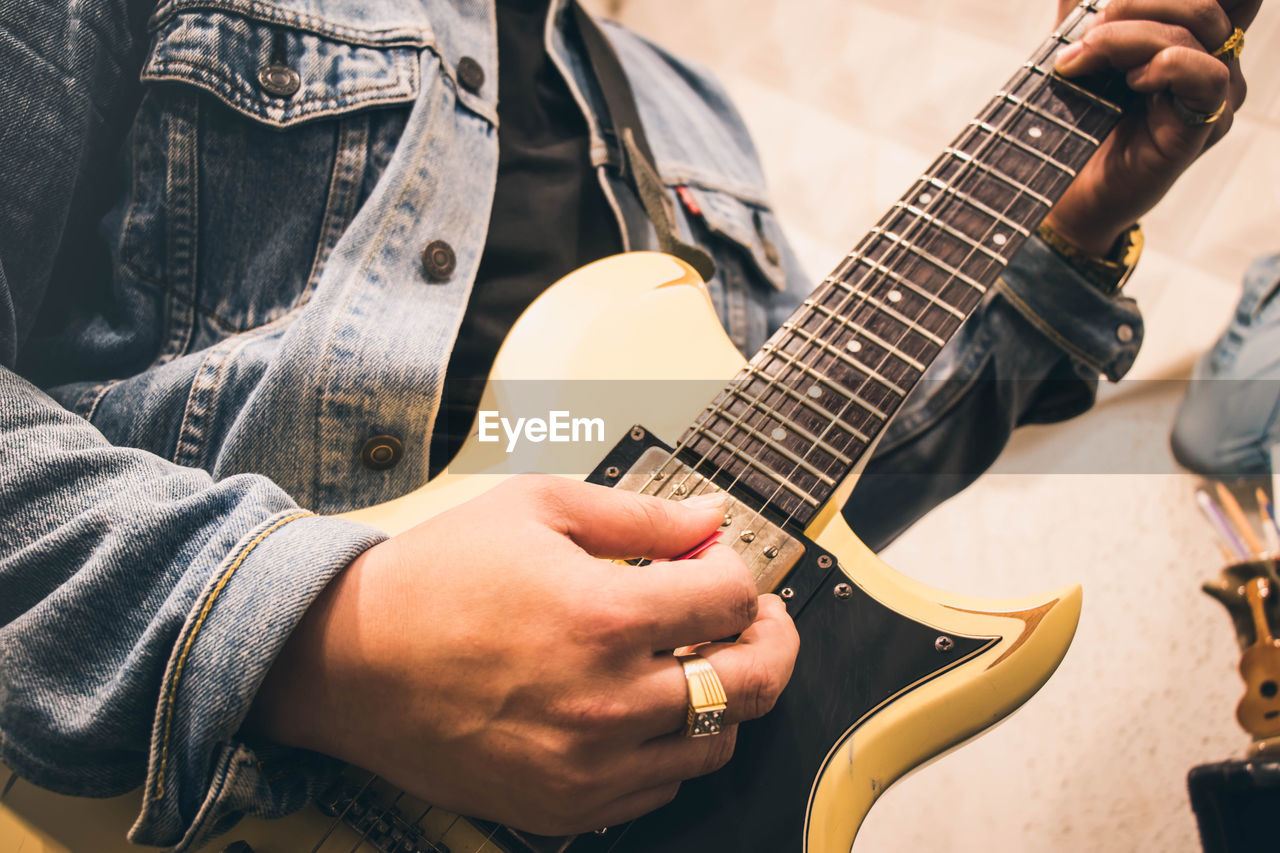 Midsection of man playing guitar