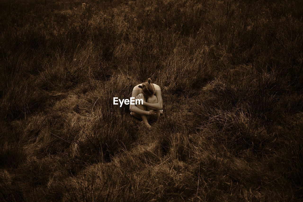 High angle view of depressed woman sitting on grass