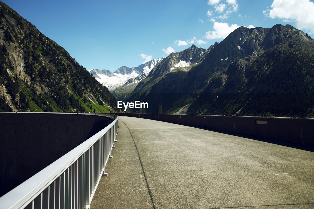 Road leading towards mountains against sky