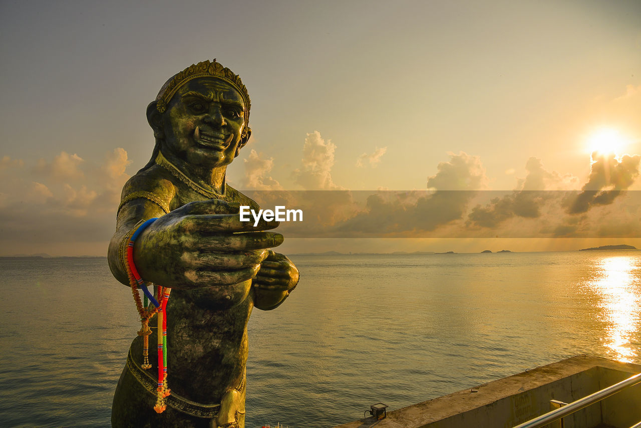 Statue by sea against sky during sunset