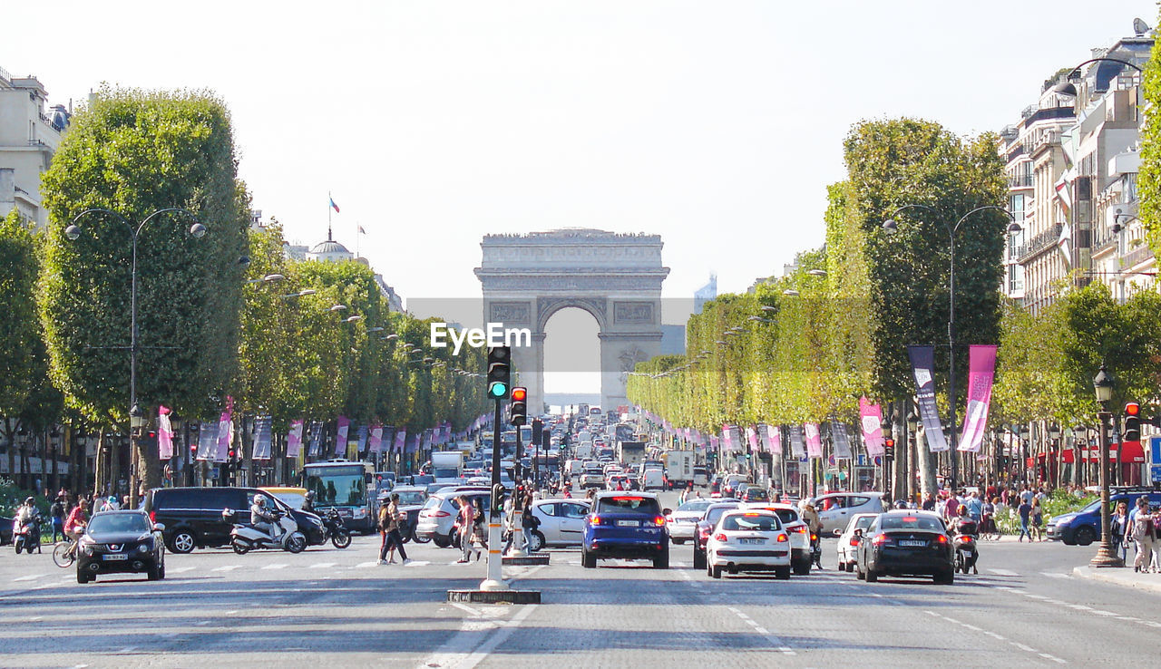 Cars on city street by arc de triomphe against clear sky