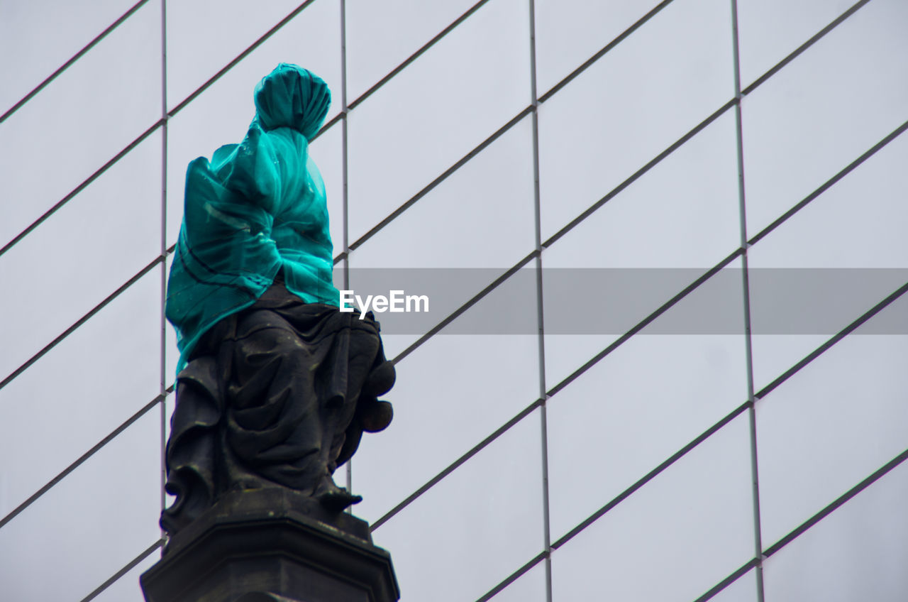 Low angle view of statue against modern building