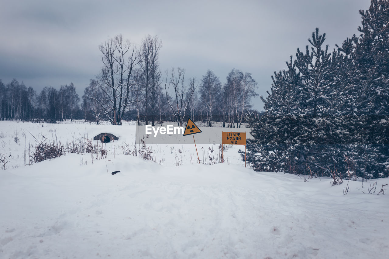 SNOW COVERED LAND BY TREES AGAINST SKY