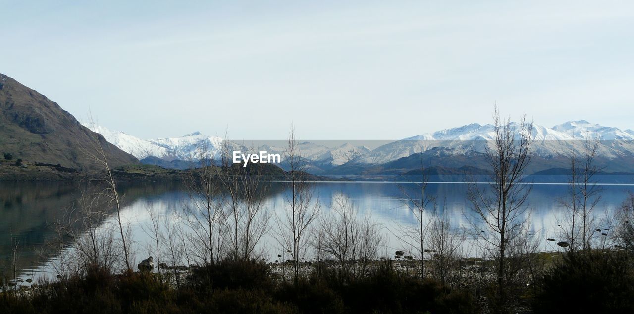 Scenic view of lake by snowcapped mountains against clear sky