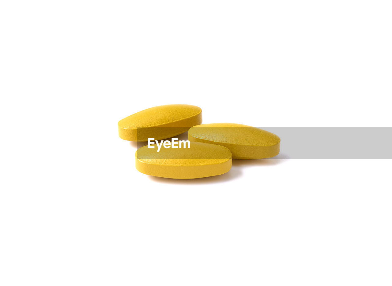 Close-up of yellow pills over white background