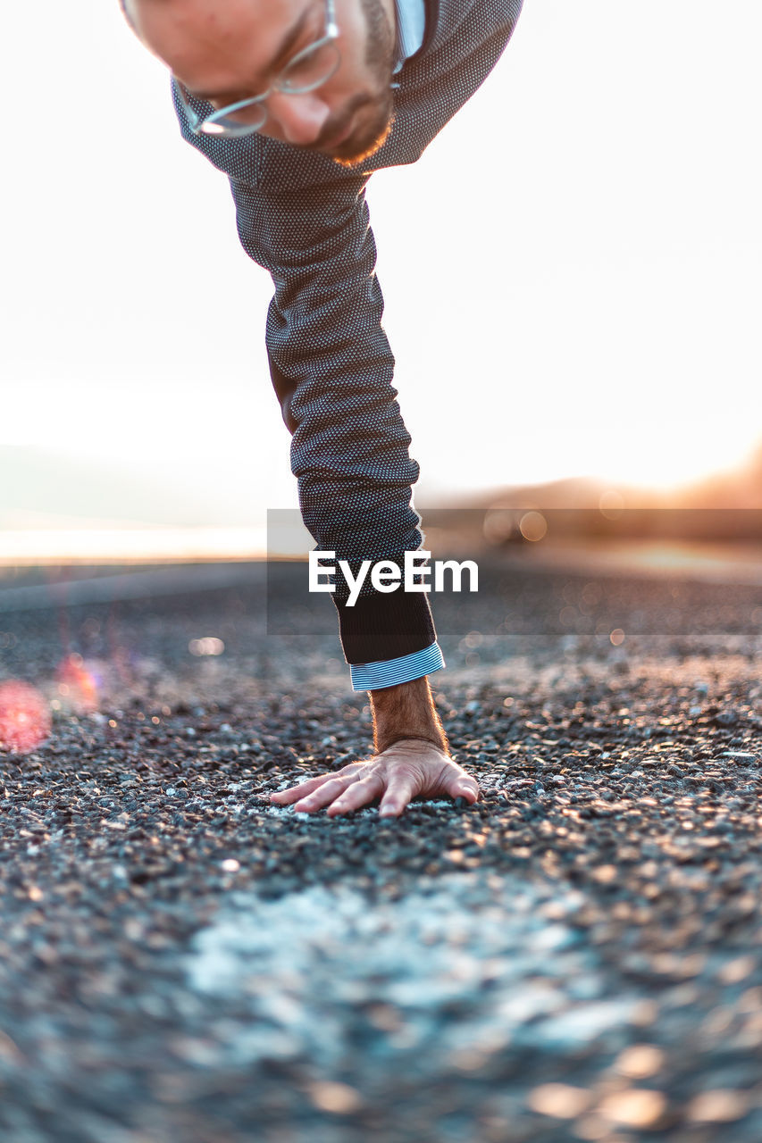 Man doing handstand on road during sunset