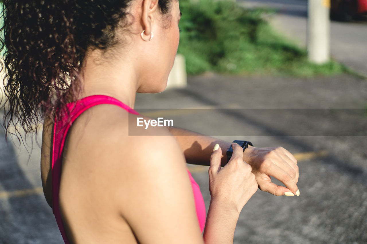 Curly young woman, wearing a fitness watch for running.