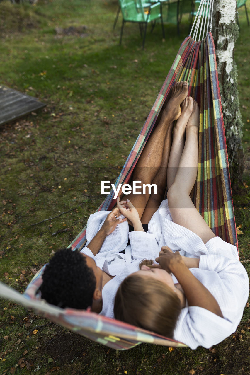 Young couple in bathrobes relaxing in hammock