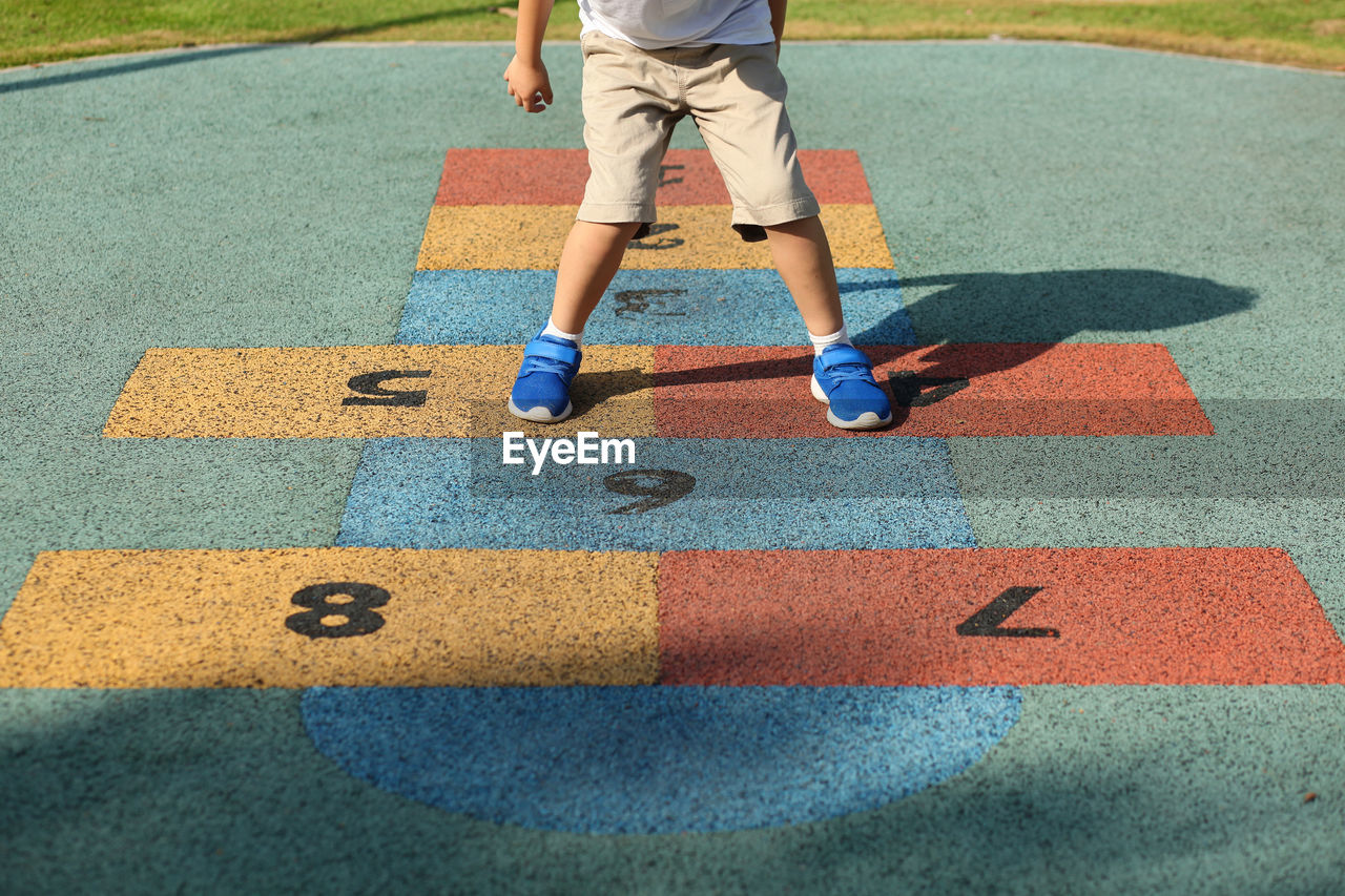 Low section of boy playing hopscotch at playground