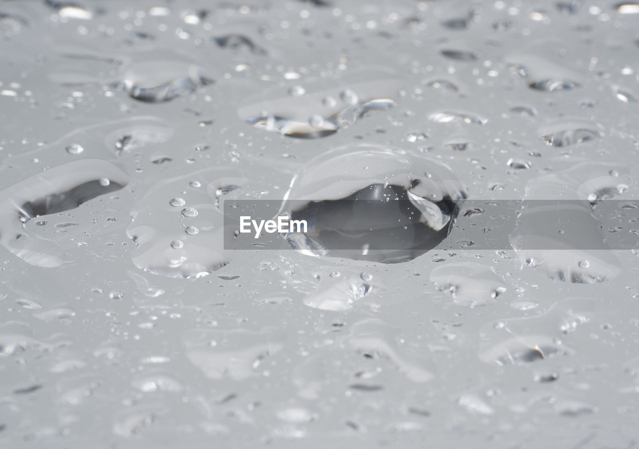 HIGH ANGLE VIEW OF WATER DROPS ON RIPPLED