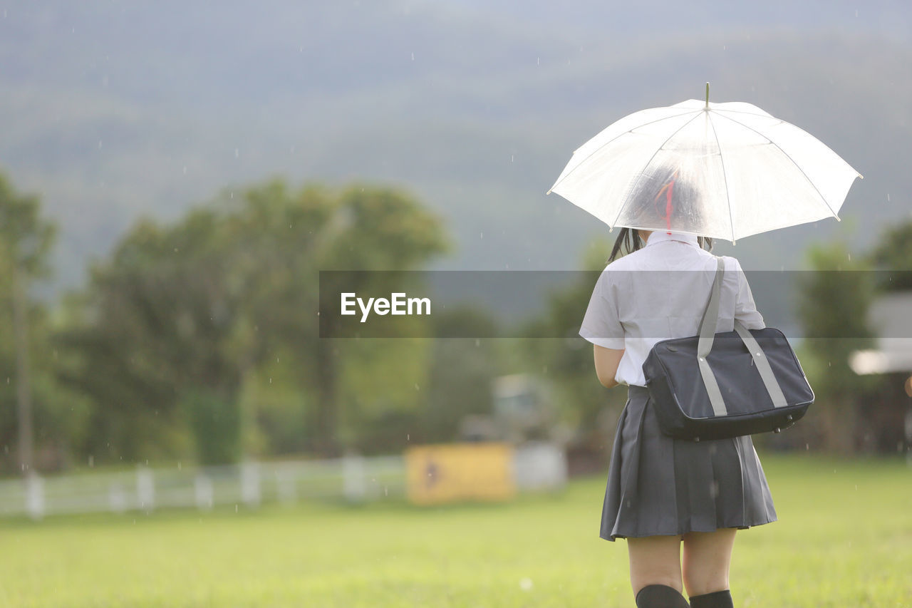 Woman with umbrella standing on field