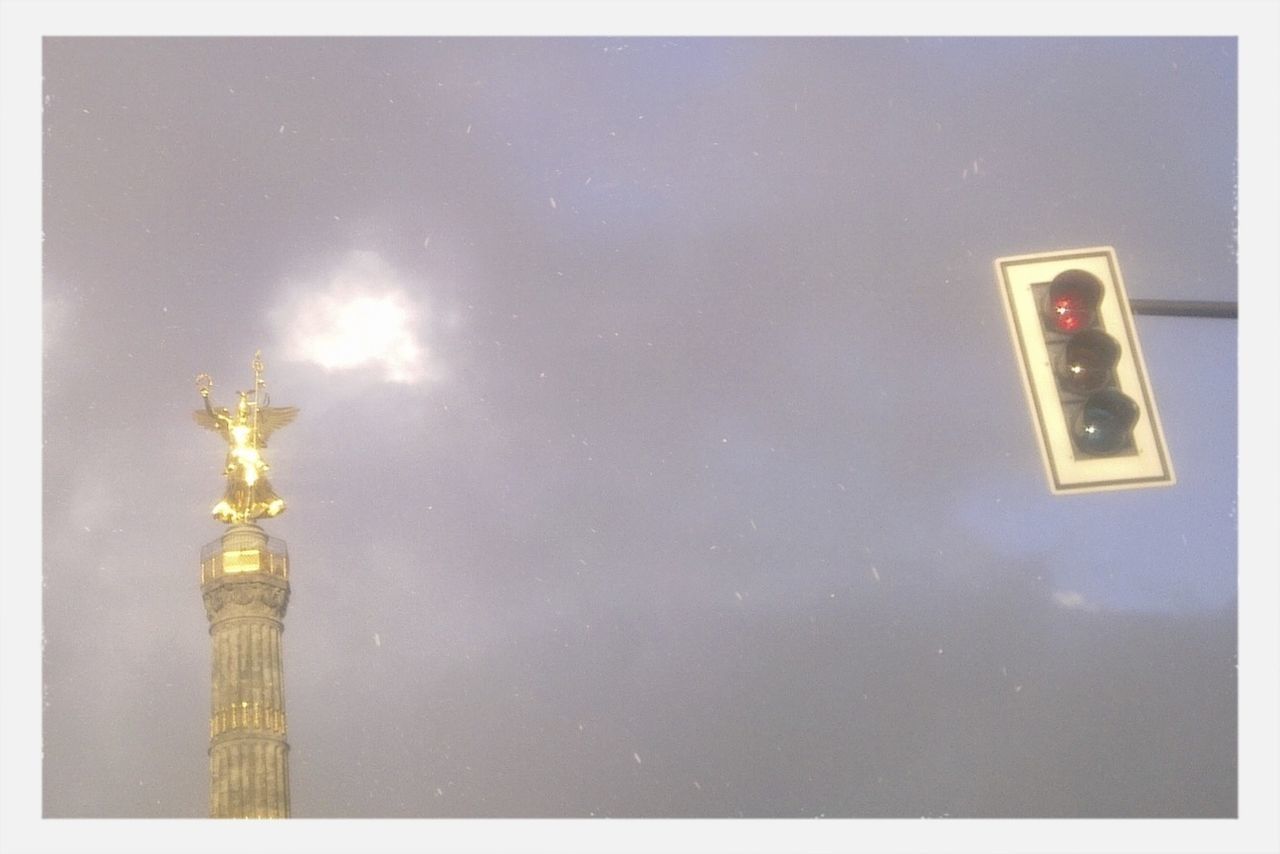 Golden statue and traffic lights against sky