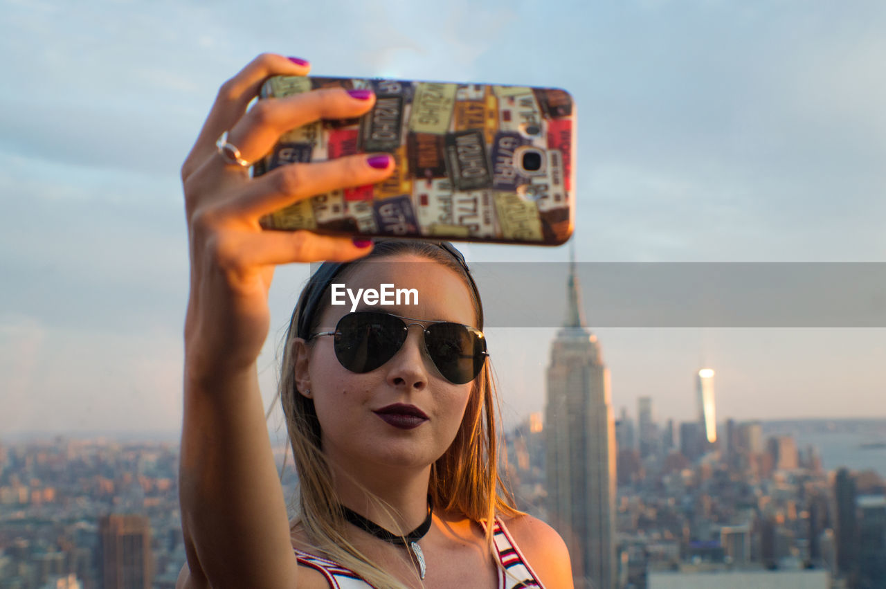 Close-up of woman taking selfie against emperor state building