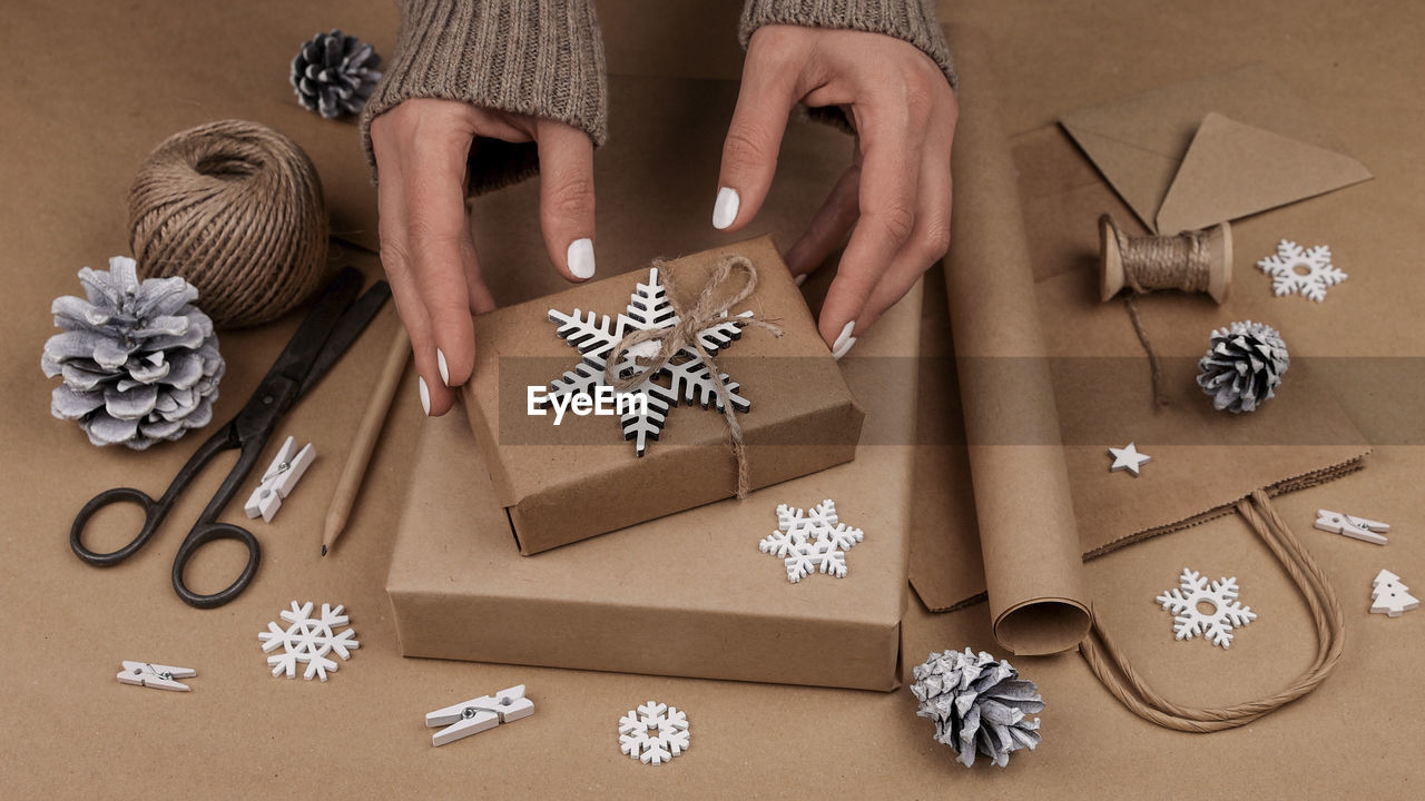 Close up woman hands packing and wrapping christmas gift boxes in natural brown paper