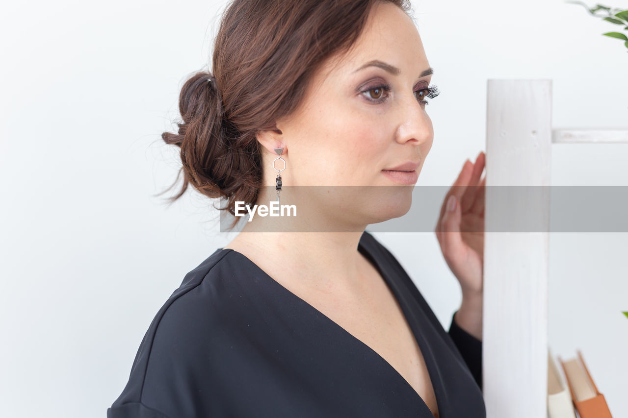 close-up of young woman looking away against white background